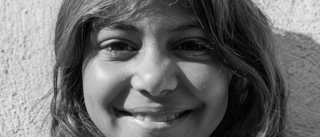 retrato de niña gitana sonriente mirando de frente a la cámara en blanco y negro