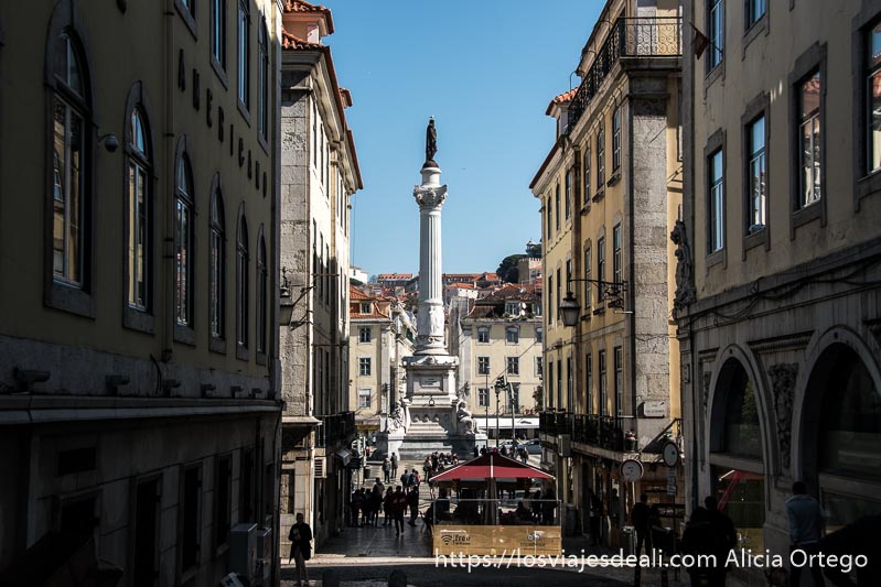estatua de la plaza de rossio vista desde una calle lateral con cielo muy azul en el centro de lisboa