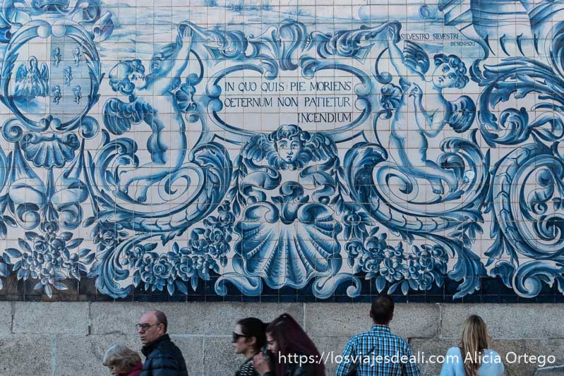 azulejos de colores azules donde se ve a unos ángeles y gente pasando delante de ellos razones para viajar a oporto