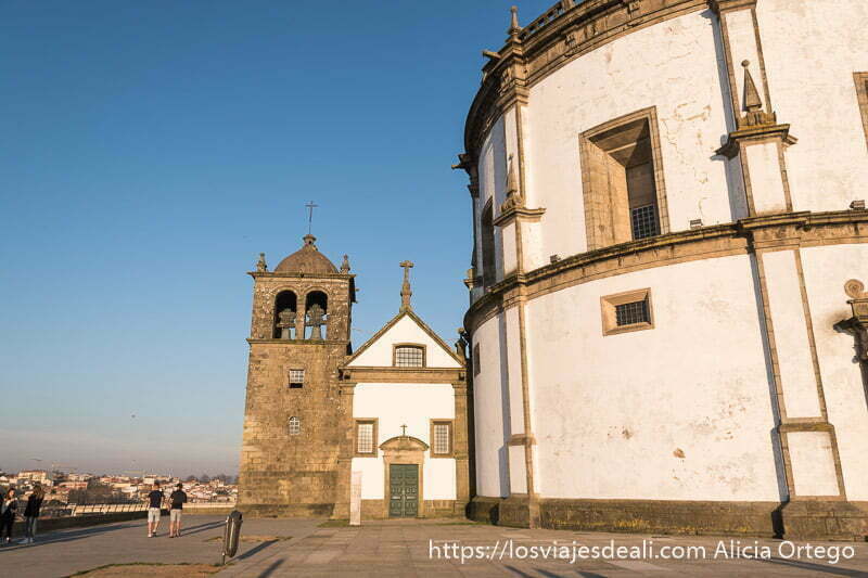 monasterio con edificio de forma circular y al lado pequeña iglesia con campanario al lado en piedra y paredes blancas en oporto