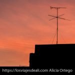 antena de televisión sobre tejado con cielo rojo de atardecer viajar desde casa