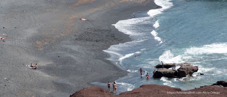 Ruta por la costa oeste de Lanzarote para 1 día 3 plaza de arena negra con gente bañándose en la costa oeste de lanzarote