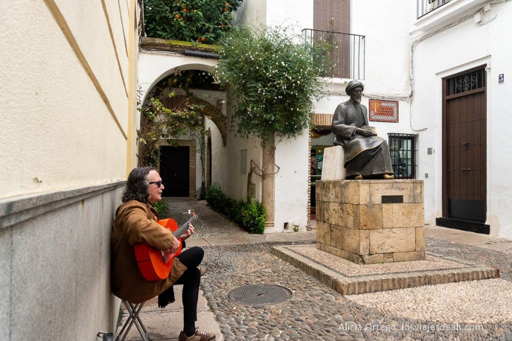 músico tocando la guitarra junto a la estatua de maimónides