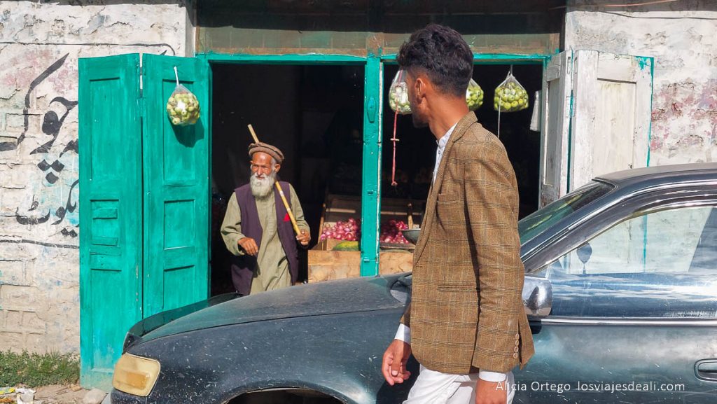 anciano saliendo de una tienda con puertas verdes