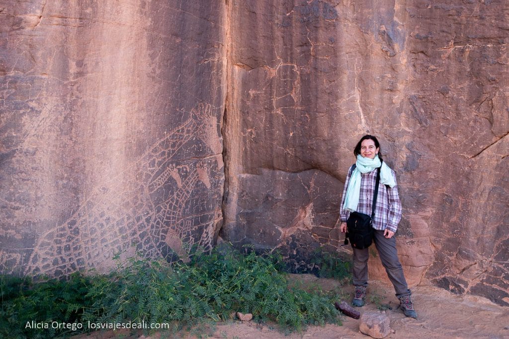 Descuentos de Viajes (Seguros, eSIM, Alojamiento) y Recursos para tu Próxima Aventura 6 posando junto a un grabado de jirafas en el desierto de argelia