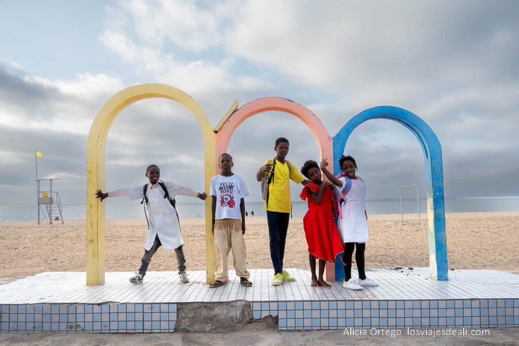 grupo de niños bajo arcos de colores con la playa detrás