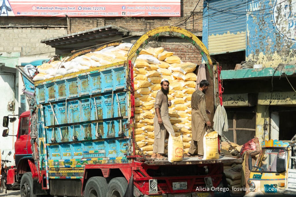 camión lleno de sacos amarillos y dos hombres descargando